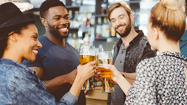 Two couples drinking beer together, both men have beards.