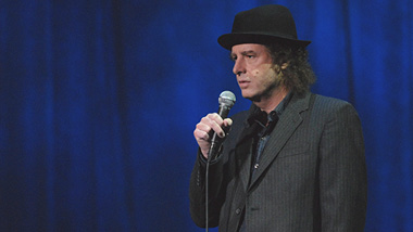 Comedian Steven Wright in a black suite and black bowler hat.