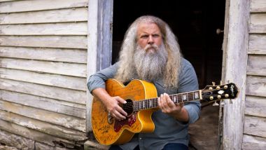 Jamey Johnson holding guitar with wooden background